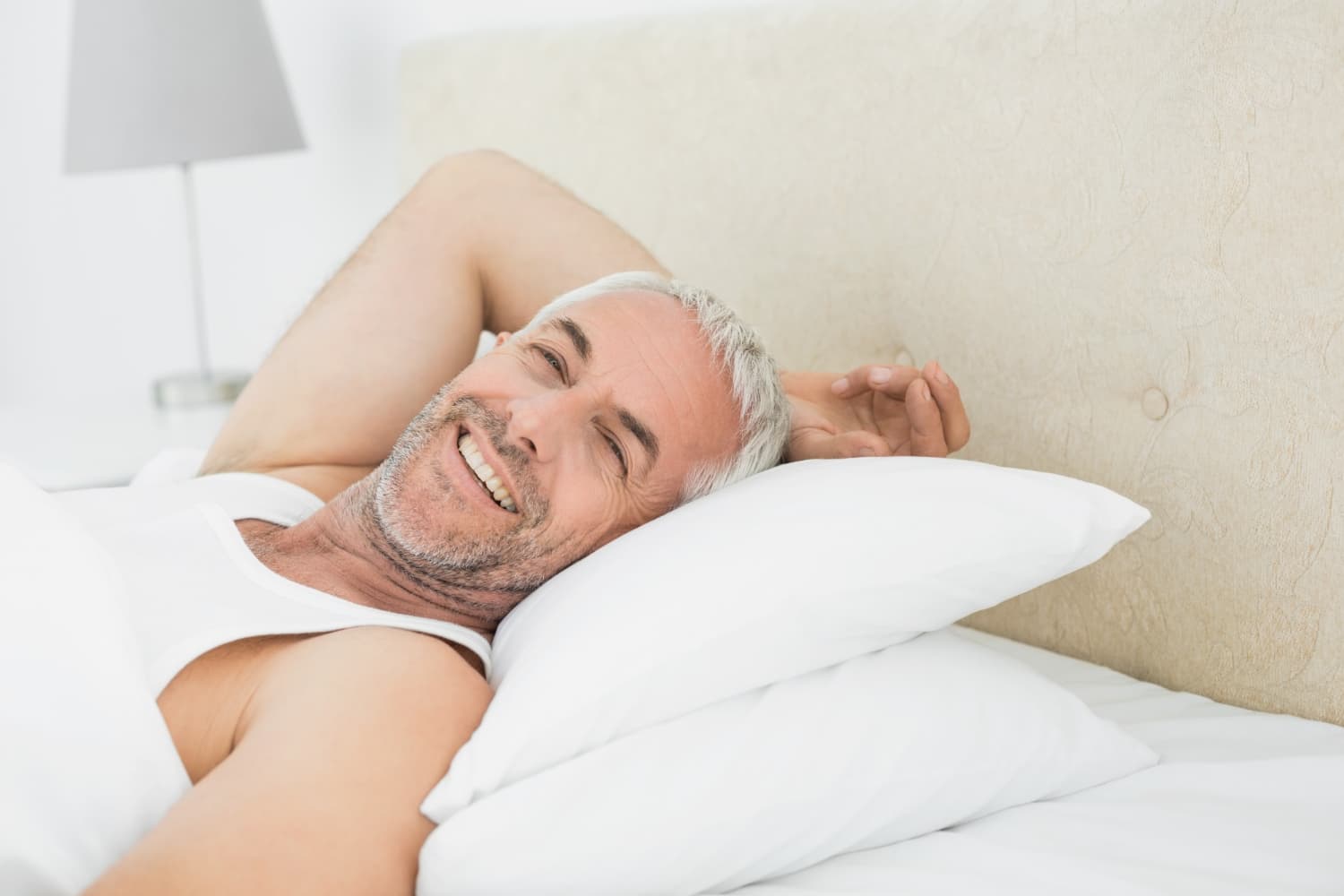 Uomo maturo sorridente e riposato a letto